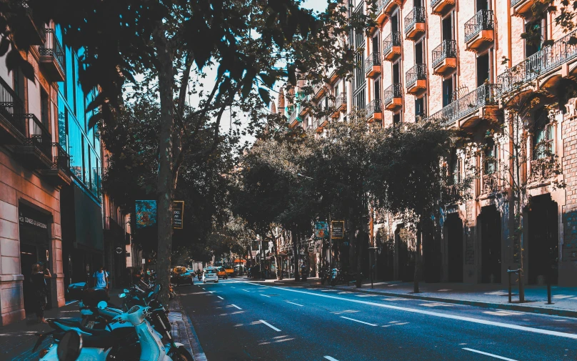 a city street filled with parked mopeds and tall buildings