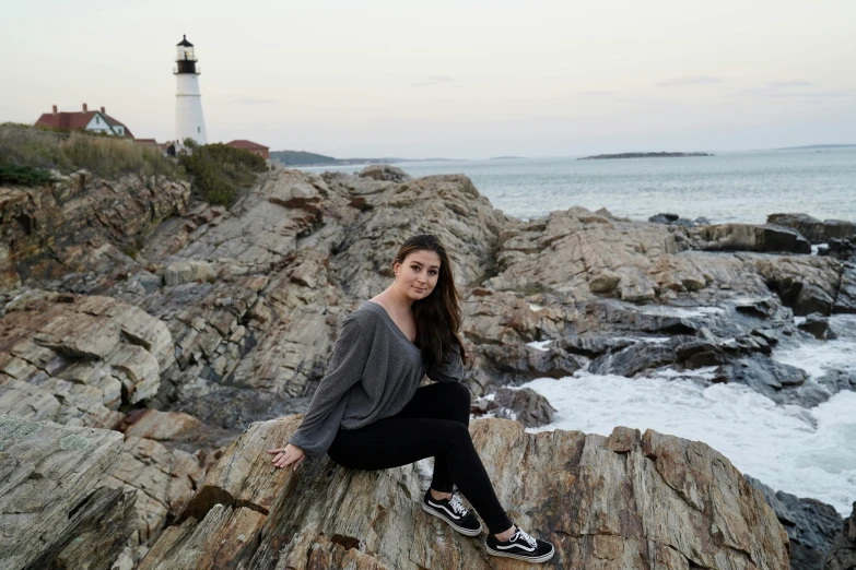 a beautiful woman sitting on top of a rock near the ocean