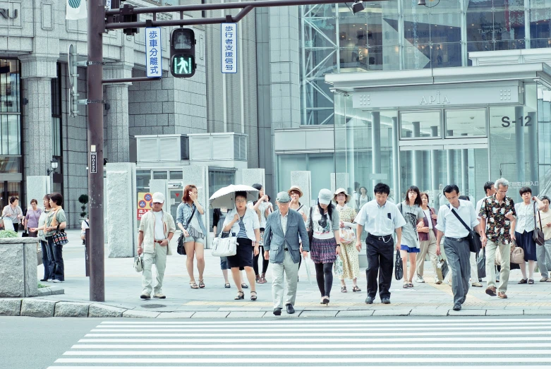 many people are crossing the street while some of them carry umbrellas