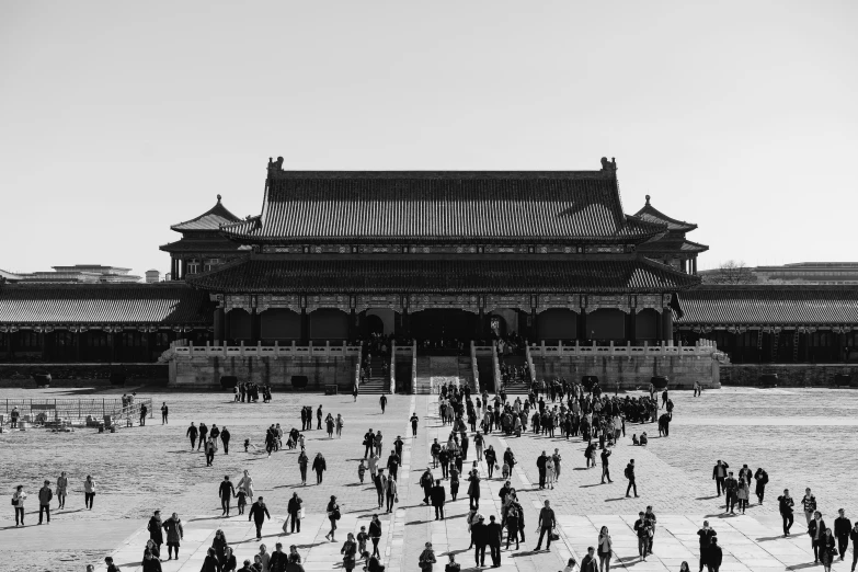 a crowd of people walk past a temple with tall windows