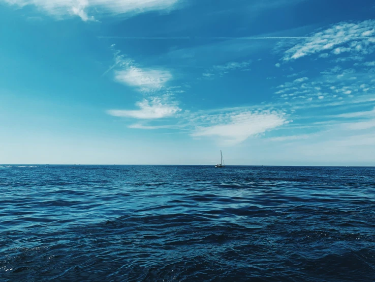 a view of the ocean from the water with blue sky and clouds above