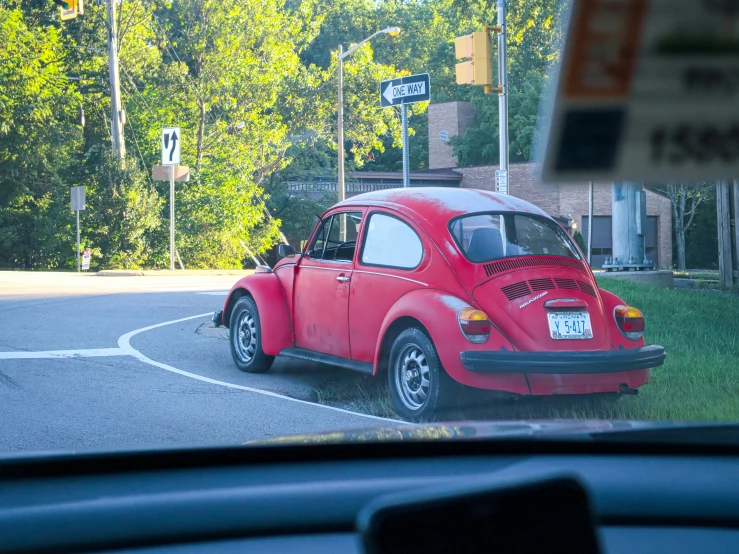 the old red vw bug is parked on the street