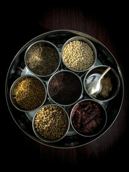 six spices are in dishes and each has their own own spoon