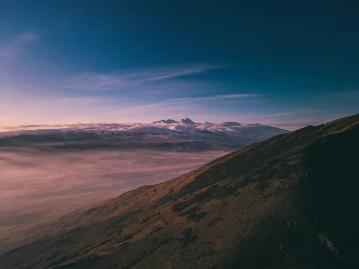 the clouds are over the mountains as sun sets