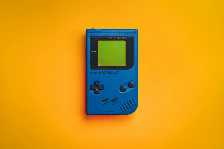 an old nintendo gameboy sitting on a bright yellow background