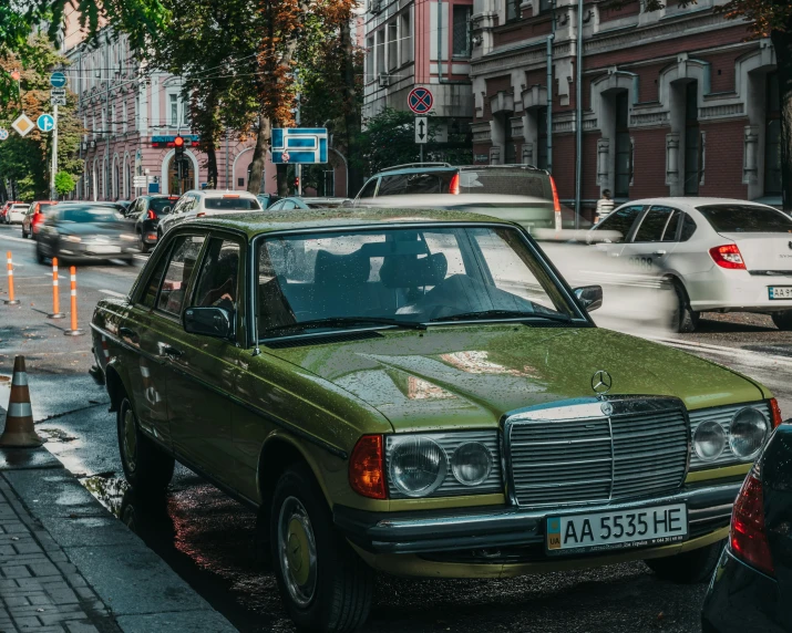 an old green mercedes on the side of the street