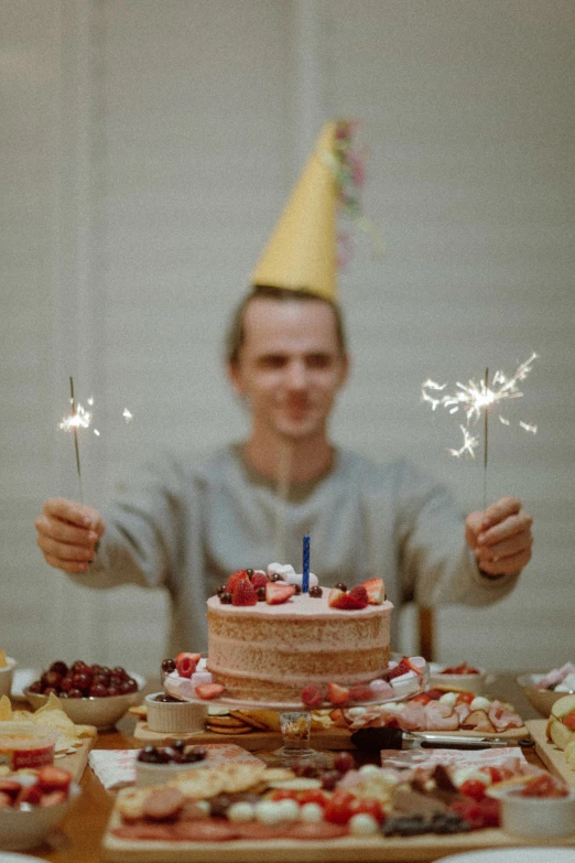 the man is holding some sparklers in front of a cake