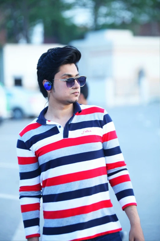 a man in striped shirt and sunglasses walking down the street