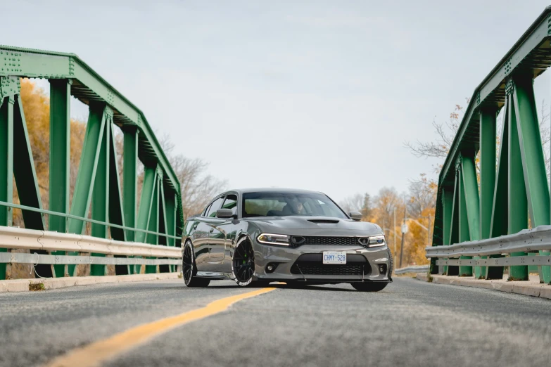 a gray mercedes drives down a bridge next to an open road