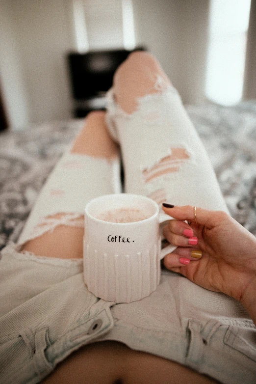 there is a woman holding a coffee mug on a bed