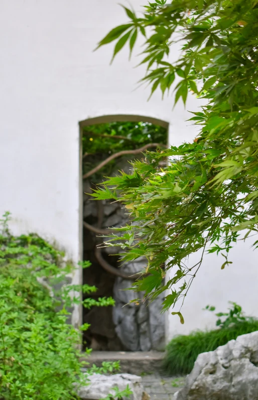 an open door on a white stucco wall next to a rock garden