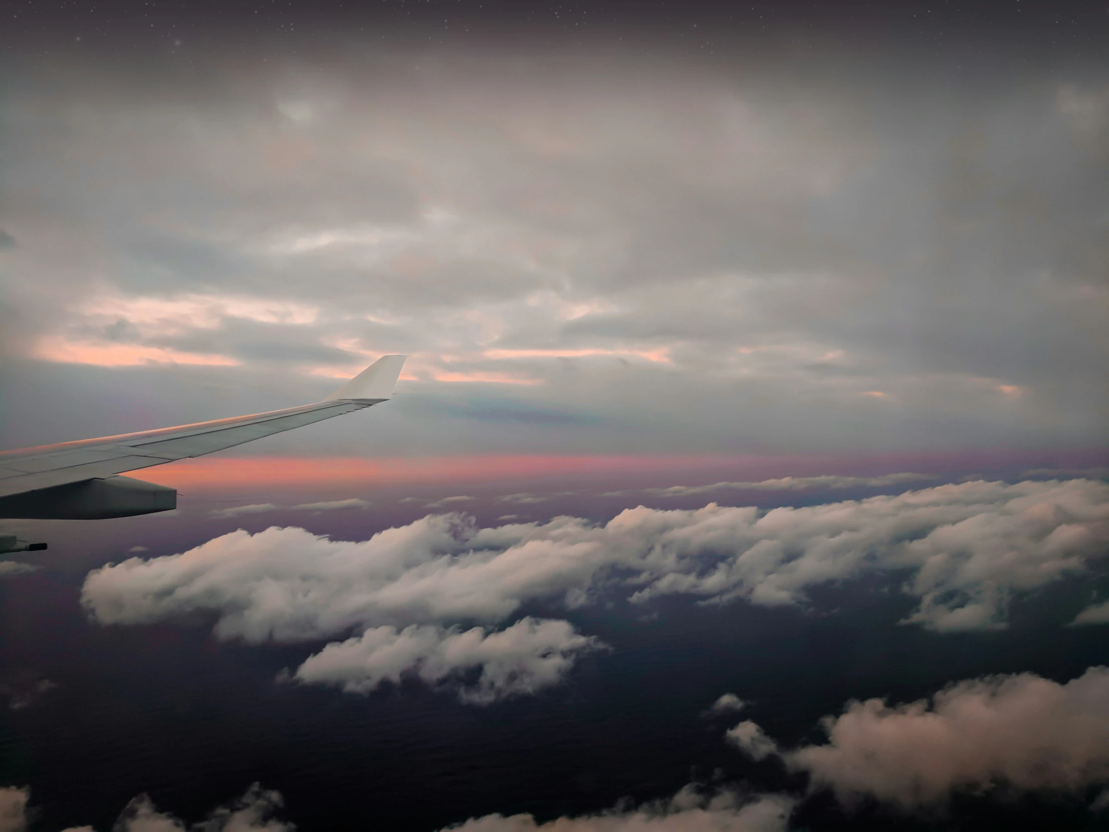 airplane wing flying over clouds under a grey sky