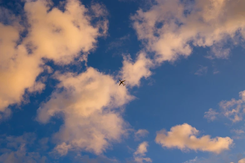 the plane is flying through the air with some clouds