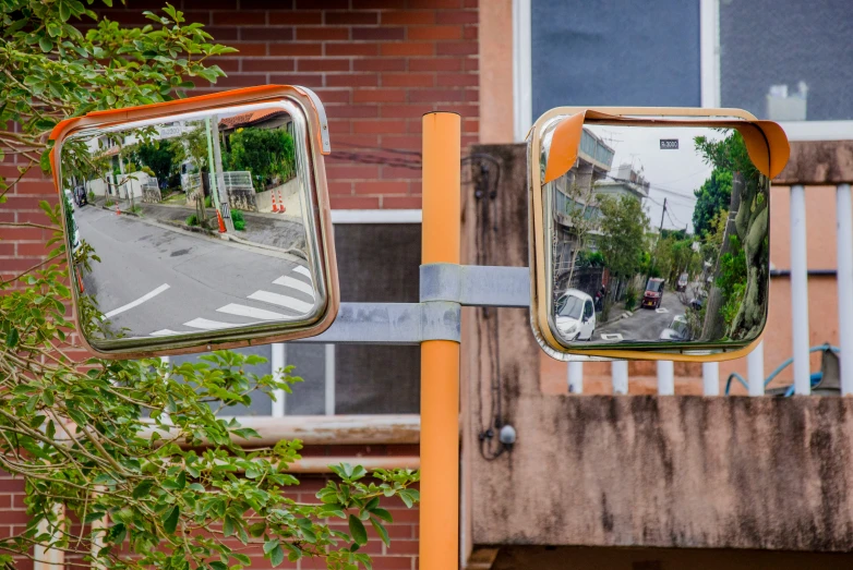 two mirrors on a metal pole in front of trees