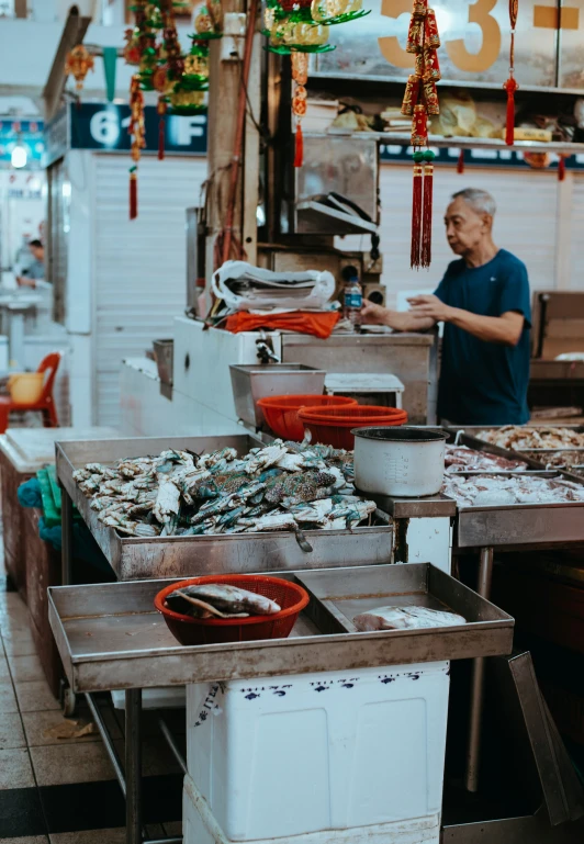 an older man working inside a shop in front of a counter full of food