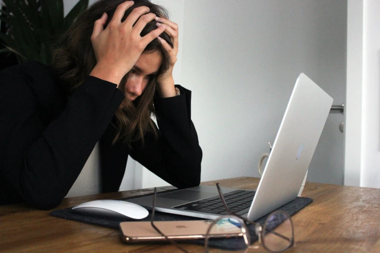 the woman is covering her eyes in front of her laptop