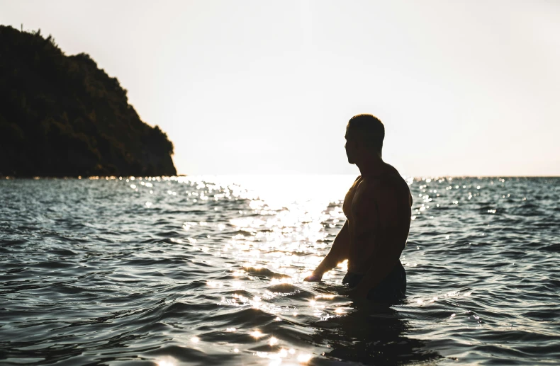 the man is standing in the ocean while getting wet