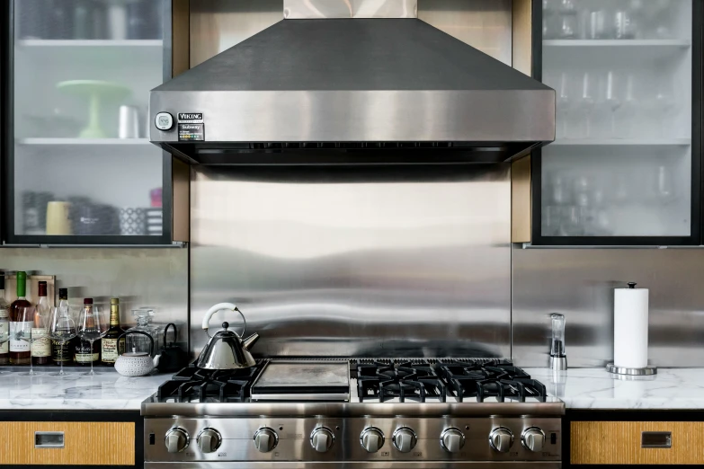 a kitchen with stainless steel oven hood and glass shelving