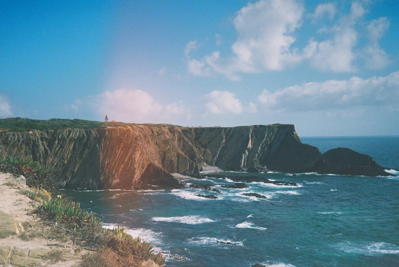 an ocean coast near some cliffs and water