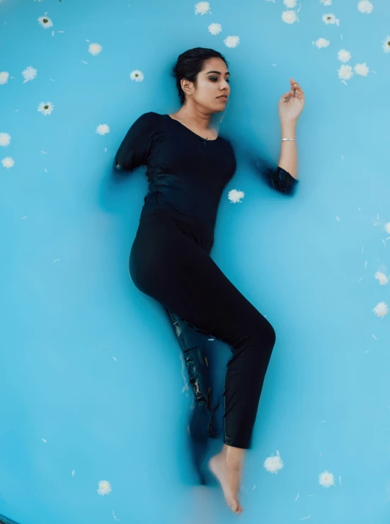 a woman wearing black laying on top of a blue pool