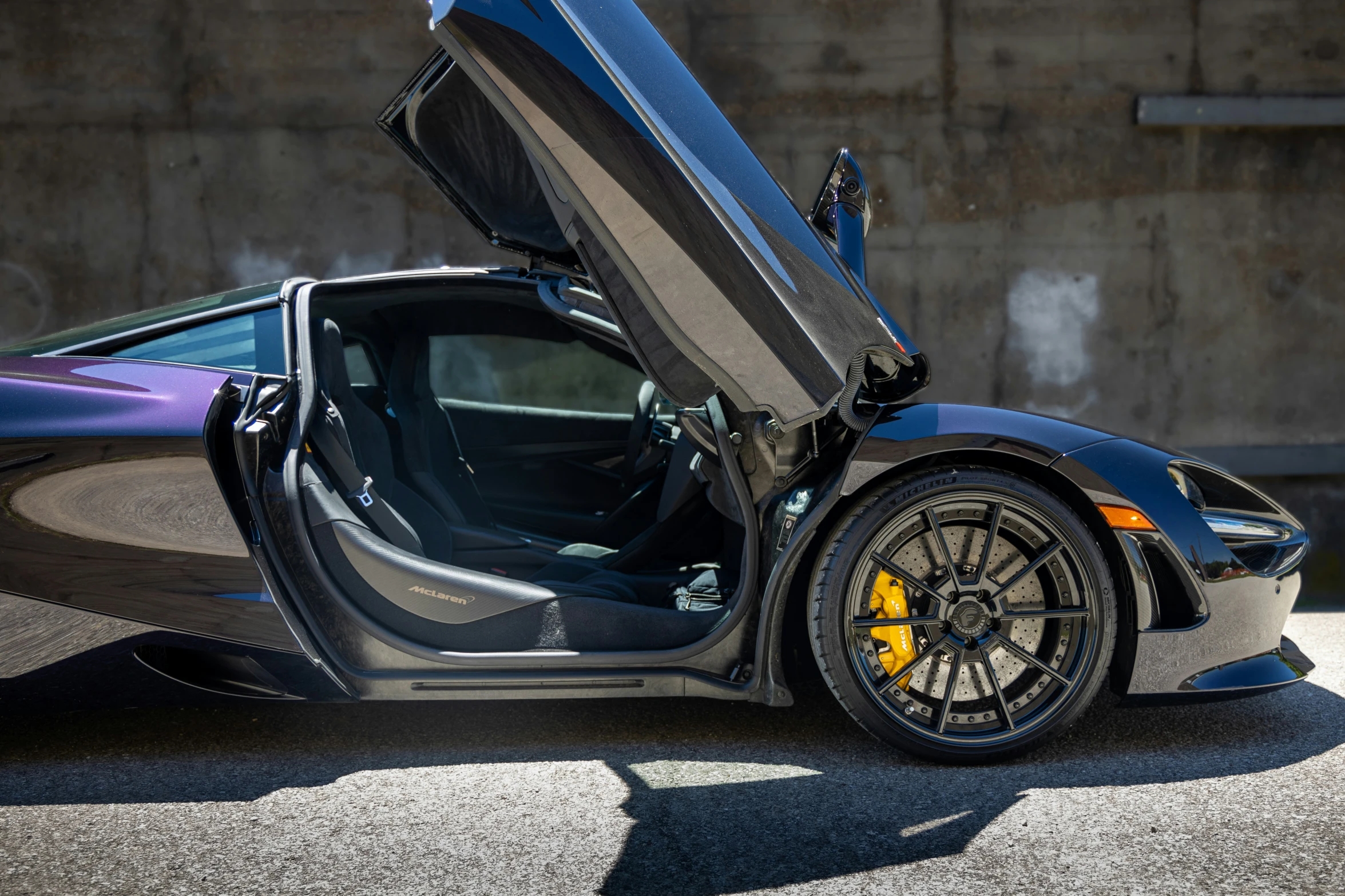 the front door of a sports car that has its trunk open