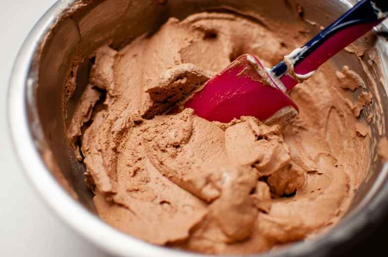 a close up of a red cup containing chocolate frosting