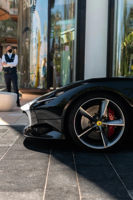 a man is standing near a black sports car