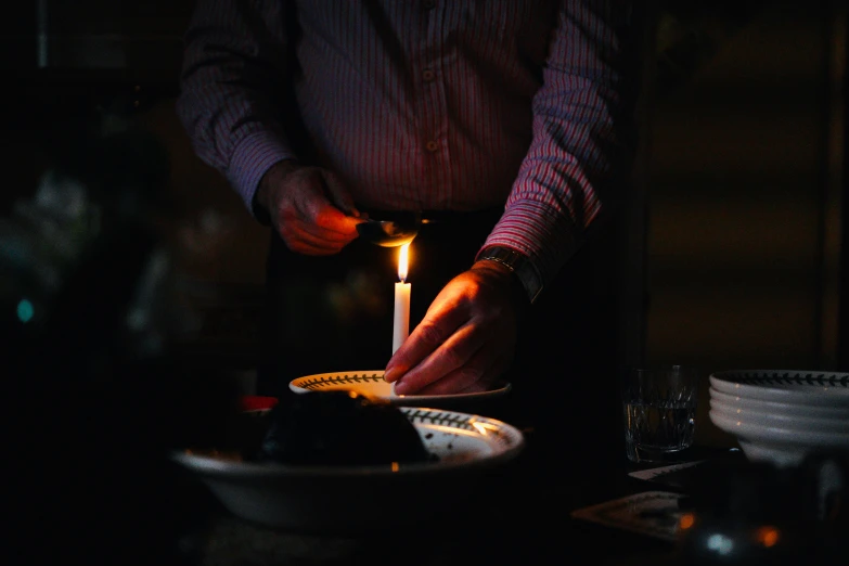 a person holding a lit candle on top of a small plate