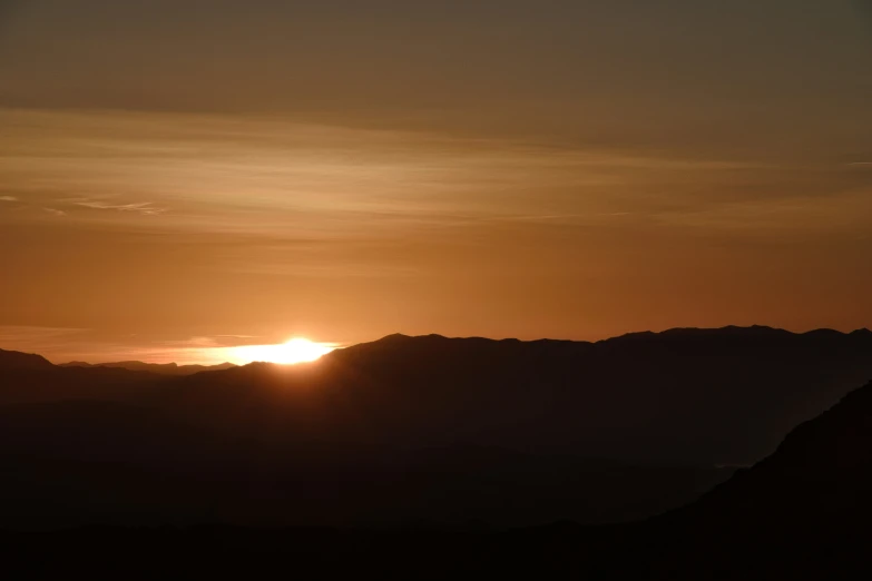 the setting sun is visible above a mountain range