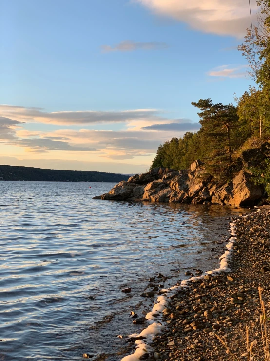 an empty rocky shore with waves and sky in the background