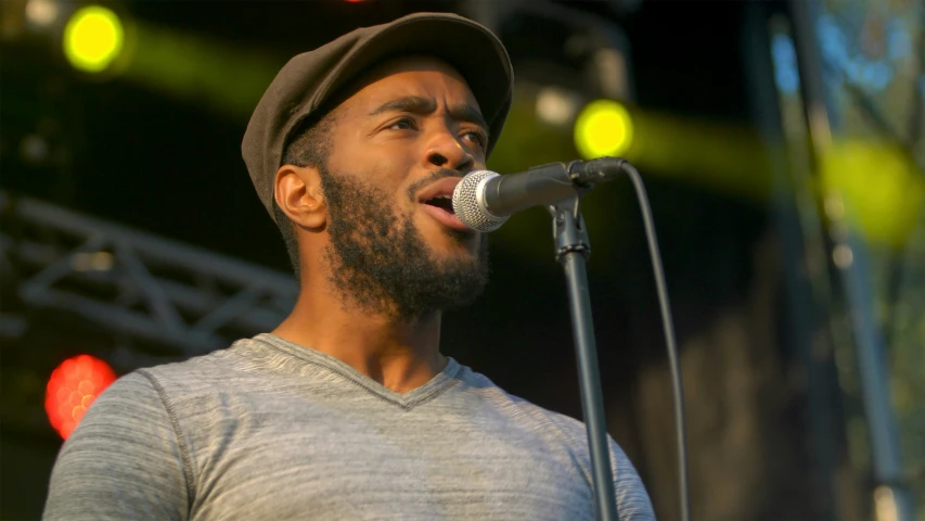 man in hat holding microphone up while performing