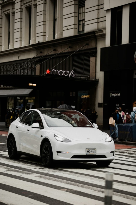 a white car driving down the street in a cross walk