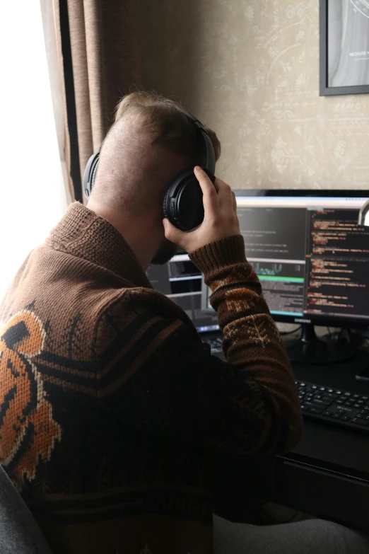 a man sitting at his computer and using the headphones