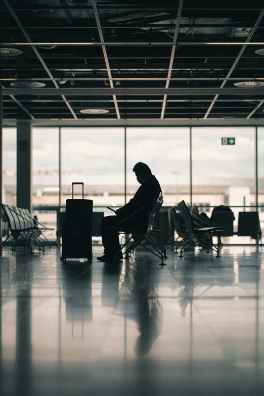 a person sitting in an airport looking out the windows