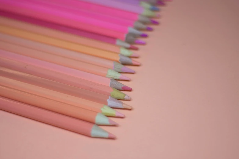 a group of colored pencils sit in rows