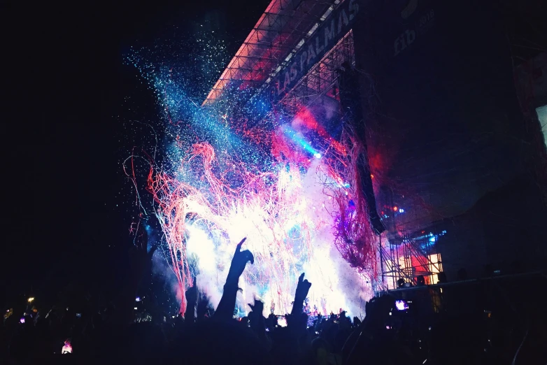 a crowd standing in front of a huge fireworks display