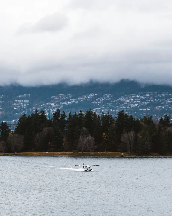 the boat is gliding down the lake under an overcast sky