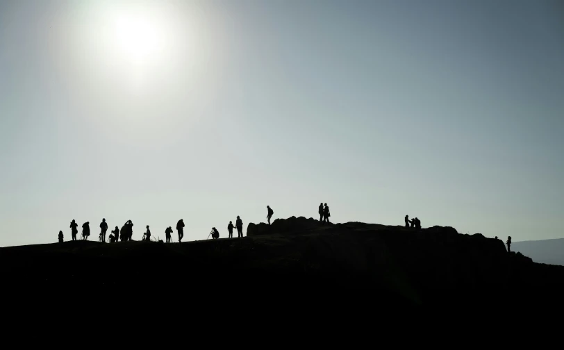 many silhouettes of people standing on a hill