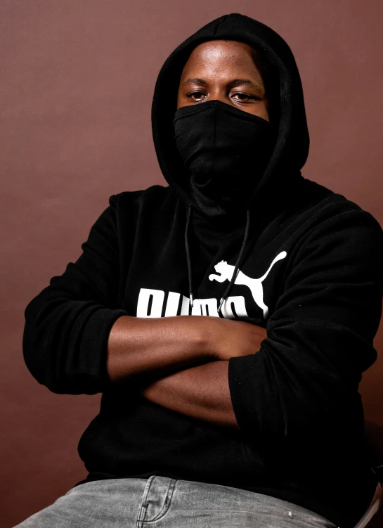 a man in black sweatshirt with hoodie and hands folded out