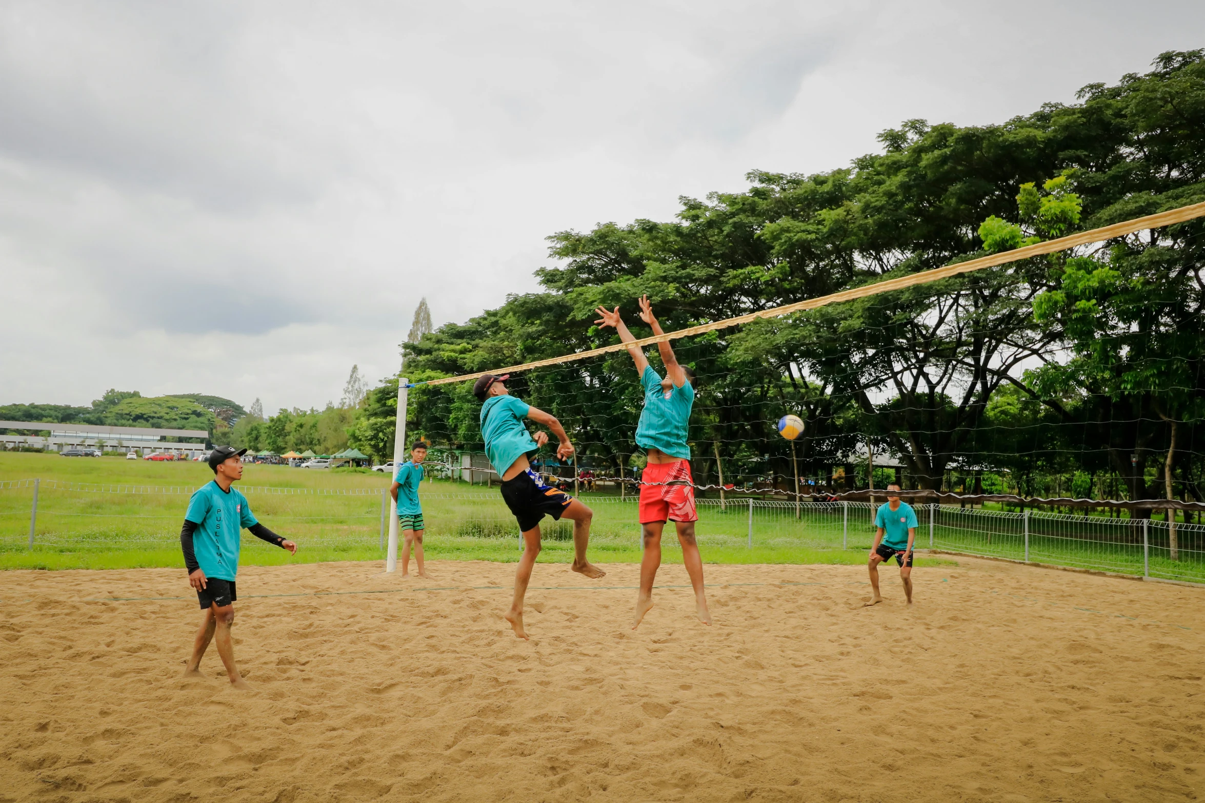 a group of young people playing volley ball on the beach