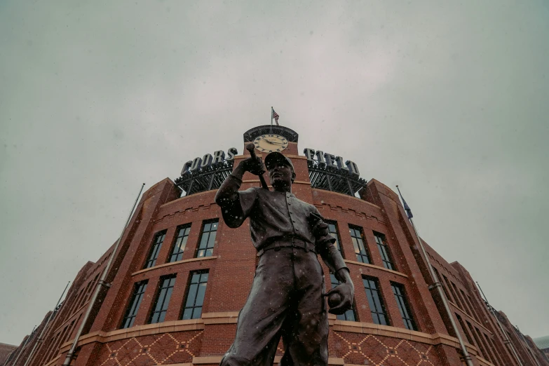 the statue stands near the brick building with windows