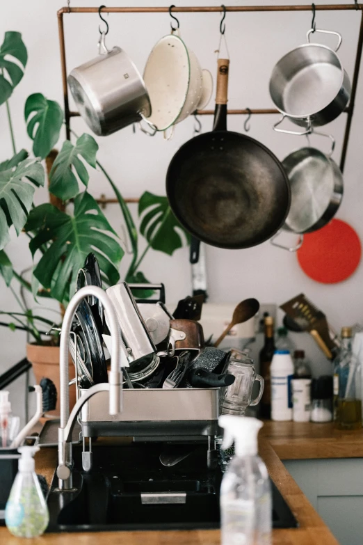 the kitchen stove has pots hanging off of it