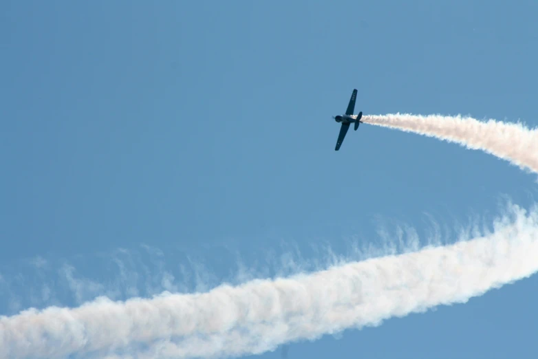 two planes leave smoke behind them while flying