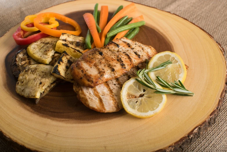 a plate with meat, vegetables and sliced lemons