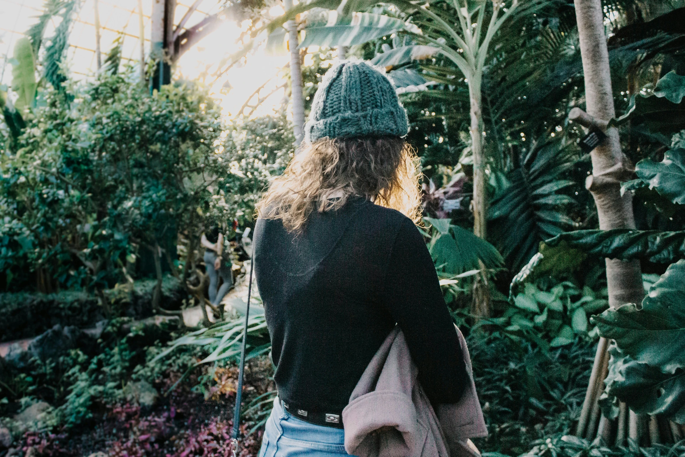 a woman in a hat is in the middle of plants