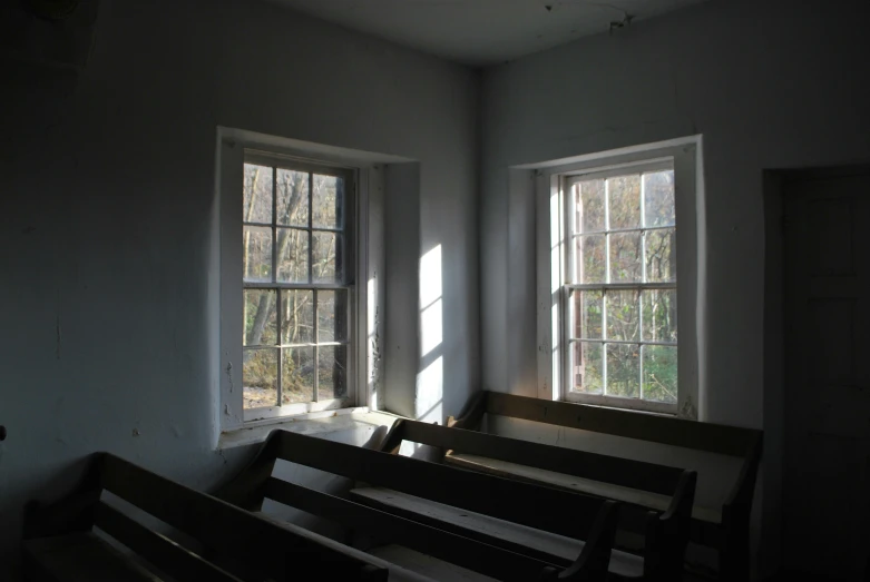 a row of wooden pews sitting in front of two windows