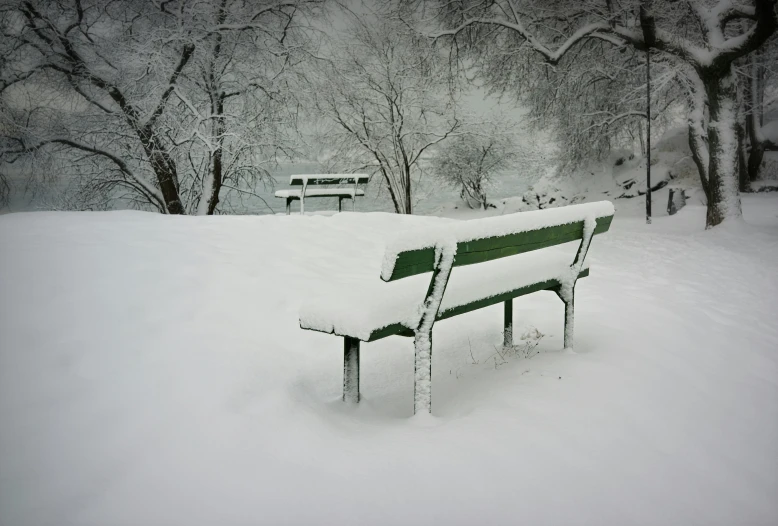 a park bench is covered in heavy snow