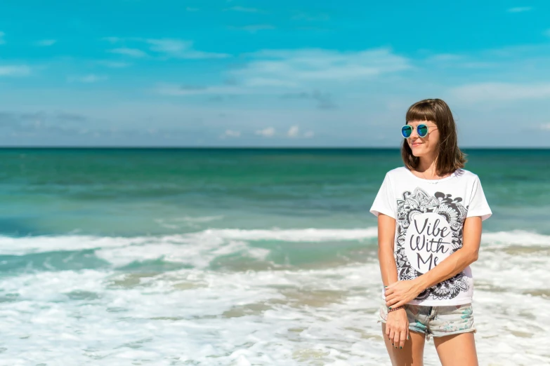 a woman is standing on a beach wearing sunglasses