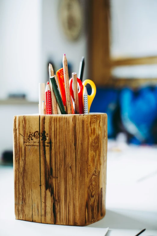 there is pencils in a wooden container on a table