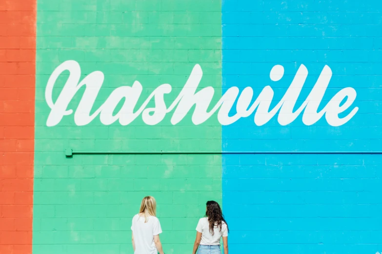 two women walking past a nashville sign